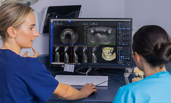 Photograph showing dental surgeons Georgia Barron and Elizabeth Morris looking at a CT scan and an intraoral scan in preparation for an inplant placement.